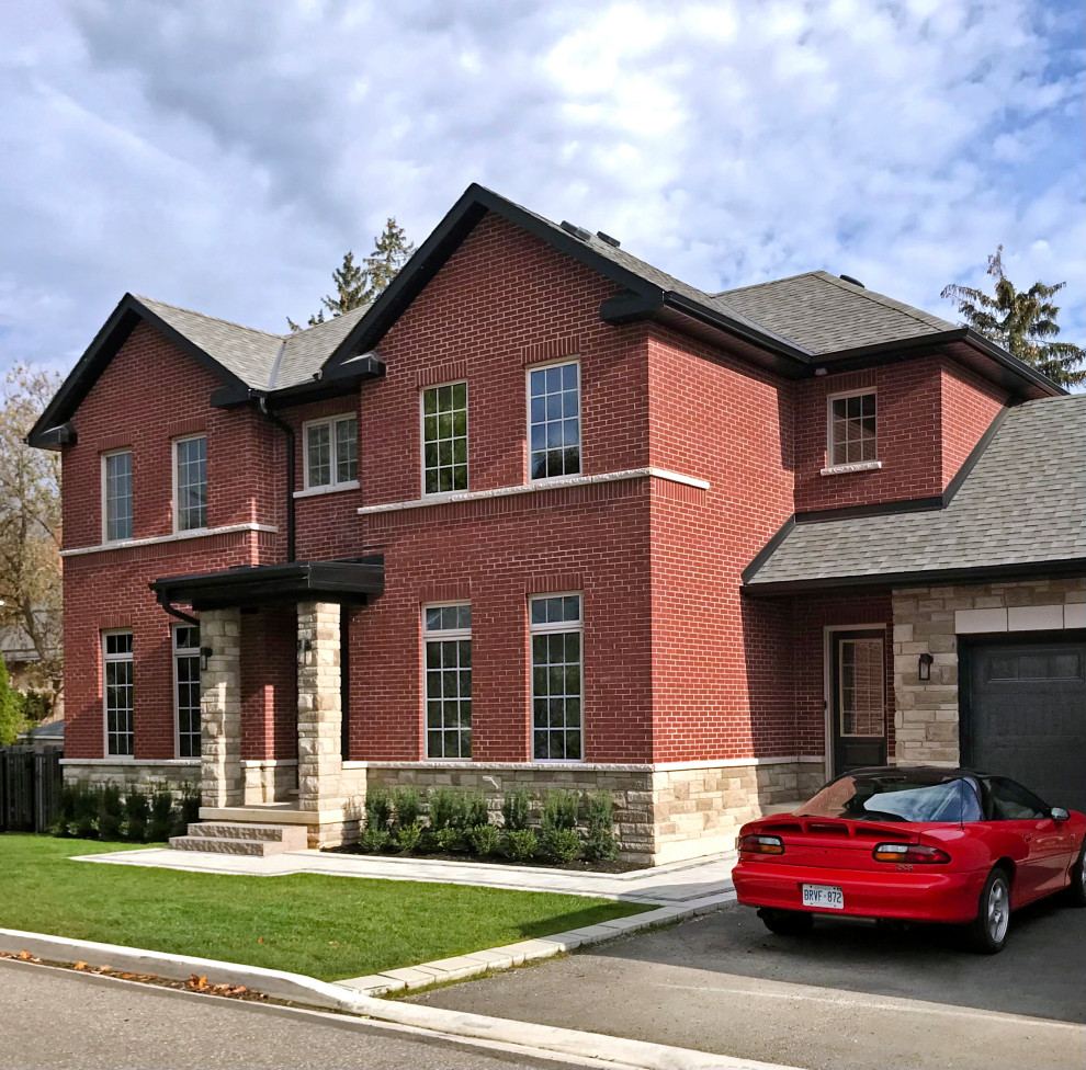Large traditional brick red house exterior in Toronto with a shingle roof and a grey roof.