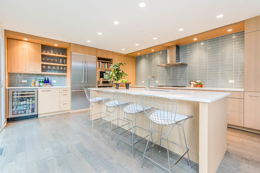 Design ideas for a large modern l-shaped eat-in kitchen in Chicago with an undermount sink, flat-panel cabinets, light wood cabinets, quartz benchtops, blue splashback, glass tile splashback, stainless steel appliances, medium hardwood floors, with island and grey floor.