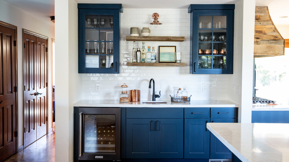 Inspiration for a mid-sized transitional single-wall wet bar in Phoenix with an undermount sink, shaker cabinets, blue cabinets, quartz benchtops, white splashback, subway tile splashback, medium hardwood floors, brown floor and white benchtop.