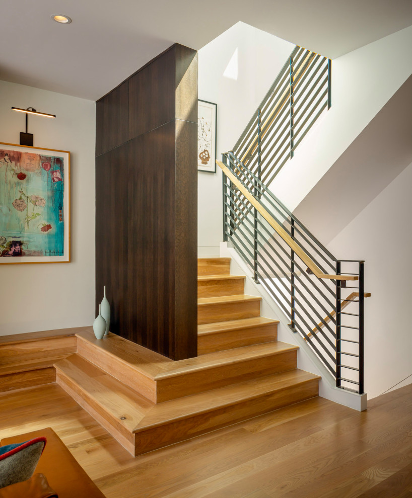 Photo of an expansive midcentury wood u-shaped staircase in San Francisco with wood risers, metal railing and wood walls.