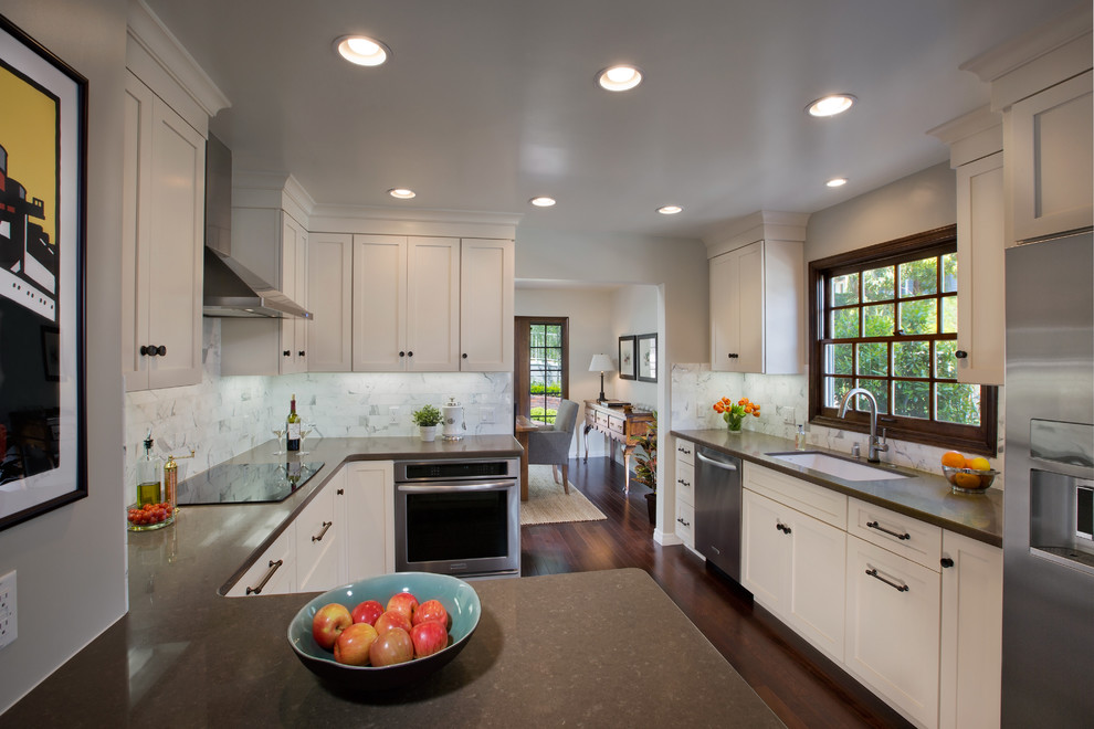 Inspiration for a traditional kitchen in Los Angeles with an undermount sink, shaker cabinets, white cabinets, terrazzo benchtops, white splashback, marble splashback, stainless steel appliances, dark hardwood floors, a peninsula and brown floor.