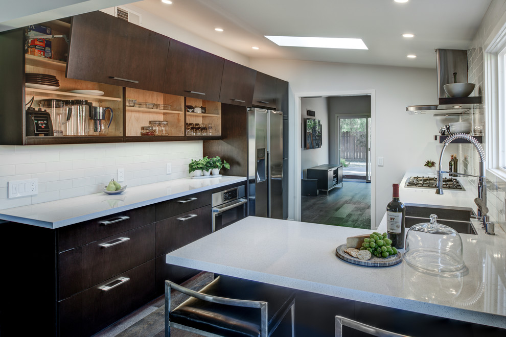 Inspiration for a small contemporary l-shaped eat-in kitchen in San Francisco with a double-bowl sink, flat-panel cabinets, dark wood cabinets, quartz benchtops, white splashback, porcelain splashback, stainless steel appliances, dark hardwood floors and a peninsula.