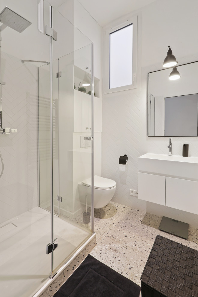 This is an example of a mid-sized contemporary master bathroom in Paris with beaded inset cabinets, white cabinets, a floating vanity, a drop-in tub, a wall-mount toilet, white walls, terrazzo floors, tile benchtops, a single vanity and wallpaper.