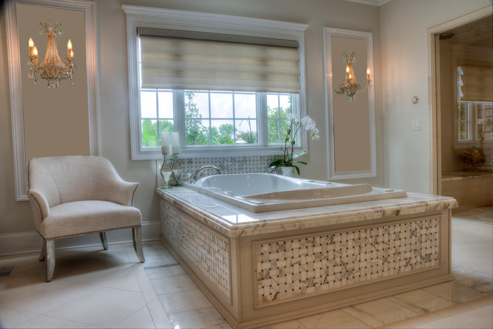 This is an example of a large traditional master bathroom in Other with an undermount sink, raised-panel cabinets, beige cabinets, marble benchtops, a freestanding tub, a one-piece toilet, black tile, stone tile, beige walls and marble floors.