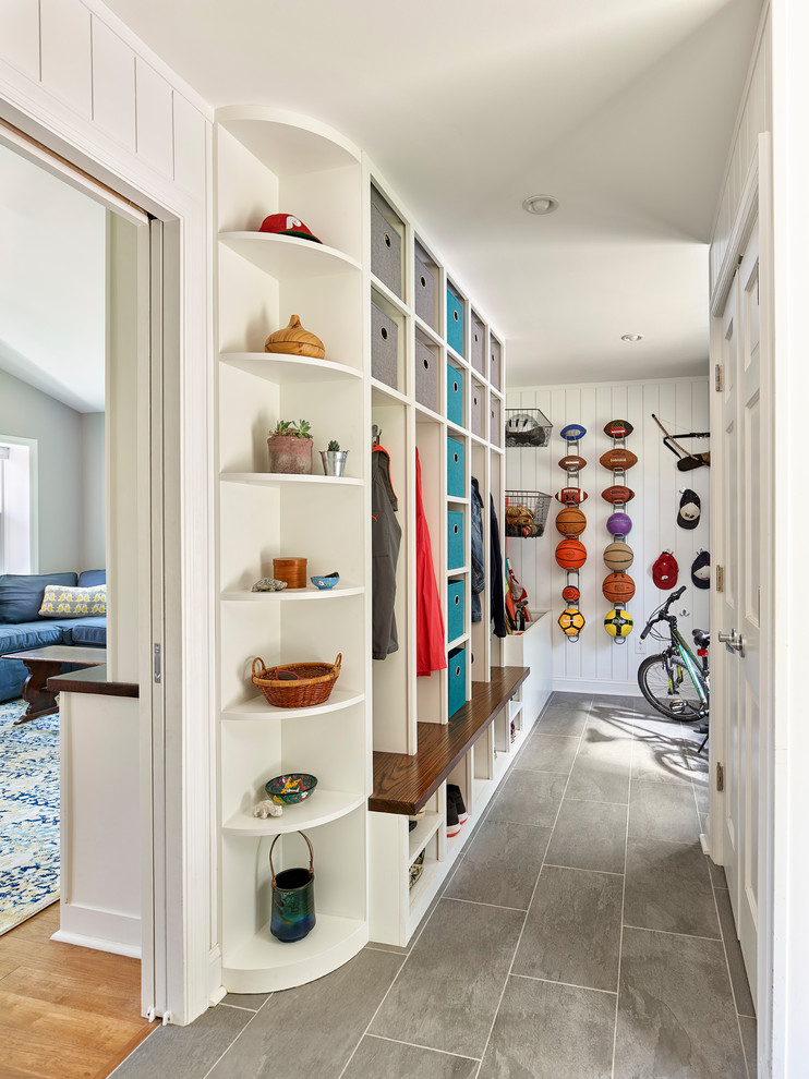 Country mudroom in Philadelphia with white walls and grey floor.