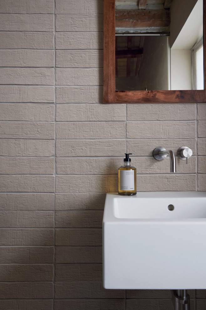 Exempel på ett rustikt beige beige badrum med dusch, med beige skåp, en kantlös dusch, en vägghängd toalettstol, beige kakel, porslinskakel, beige väggar, klinkergolv i porslin, ett integrerad handfat, kaklad bänkskiva, beiget golv och dusch med skjutdörr