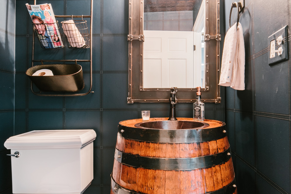 Mid-sized industrial powder room in Chicago with medium wood cabinets, a two-piece toilet, blue walls, medium hardwood floors, a drop-in sink and brown floor.