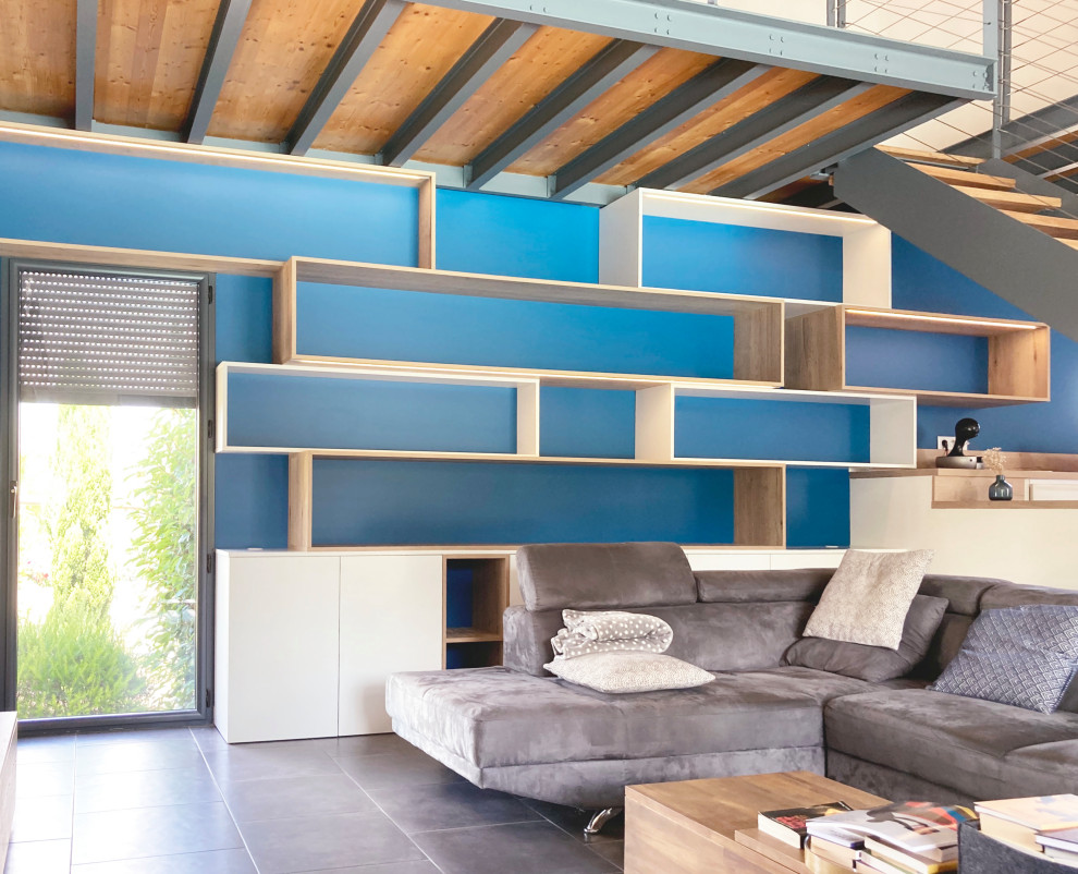 Inspiration pour un grand salon design avec une bibliothèque ou un coin lecture, un mur bleu, un sol en carrelage de céramique, aucune cheminée, un sol gris et un plafond en bois.