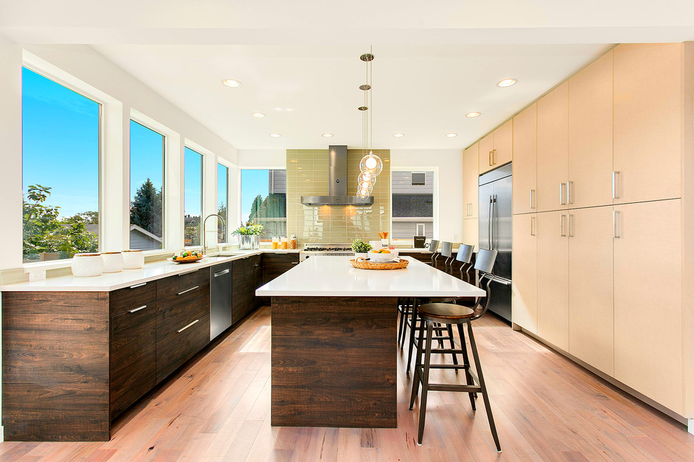 Inspiration for a large contemporary u-shaped eat-in kitchen in Seattle with an undermount sink, flat-panel cabinets, stainless steel appliances, light hardwood floors, with island, green splashback, glass tile splashback, dark wood cabinets and solid surface benchtops.