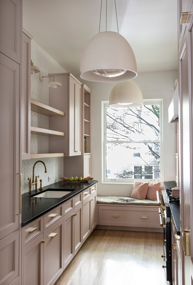 Photo of a small classic galley enclosed kitchen in New York with open cabinets, pink cabinets, soapstone worktops, white splashback, ceramic splashback and black worktops.