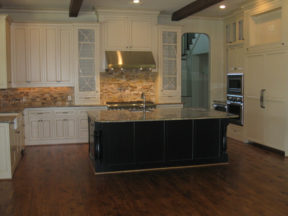 Inspiration for a large transitional u-shaped medium tone wood floor enclosed kitchen remodel in Dallas with a farmhouse sink, recessed-panel cabinets, yellow cabinets, granite countertops, beige backsplash, stone tile backsplash, white appliances and an island