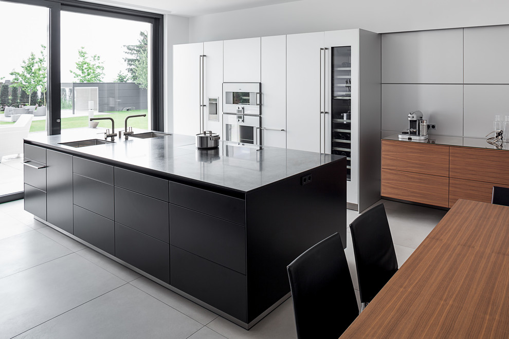 Photo of a contemporary single-wall open plan kitchen in Cologne with a double-bowl sink, beaded inset cabinets, black cabinets, stainless steel appliances, concrete floors and with island.