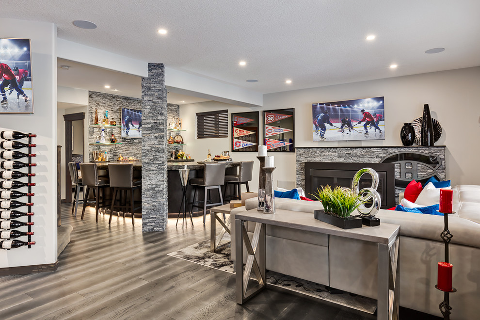 Design ideas for a large transitional walk-out basement in Calgary with grey walls, medium hardwood floors, a standard fireplace, a stone fireplace surround and grey floor.