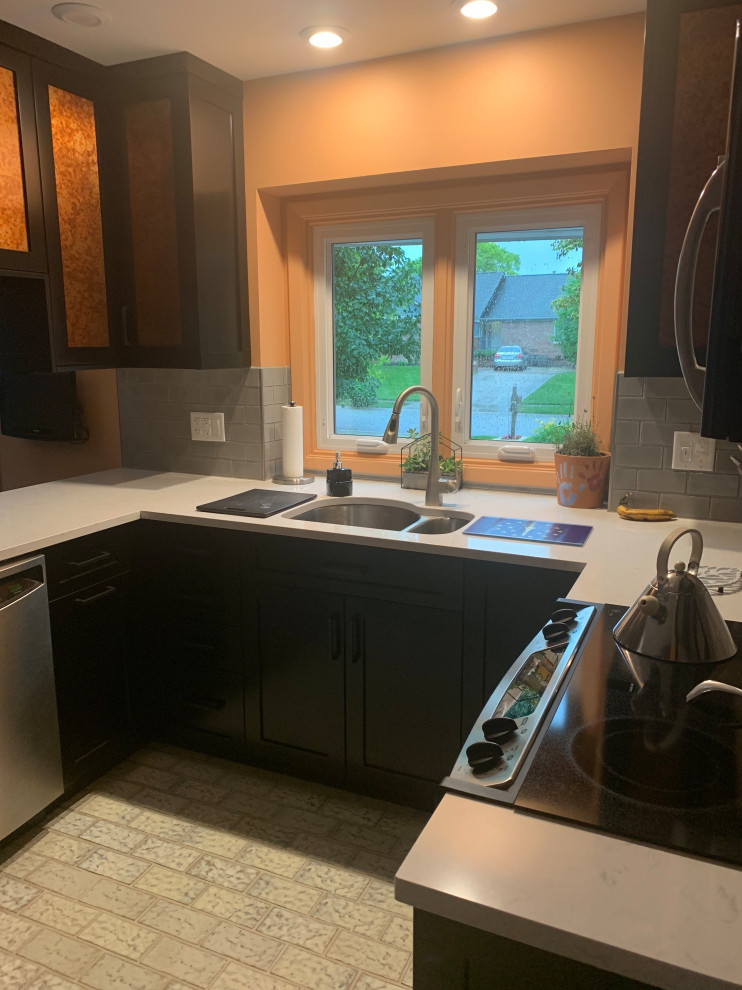 Small transitional u-shaped ceramic tile and multicolored floor enclosed kitchen photo in Indianapolis with a double-bowl sink, recessed-panel cabinets, black cabinets, quartz countertops, gray backsplash, ceramic backsplash, stainless steel appliances, a peninsula and gray countertops
