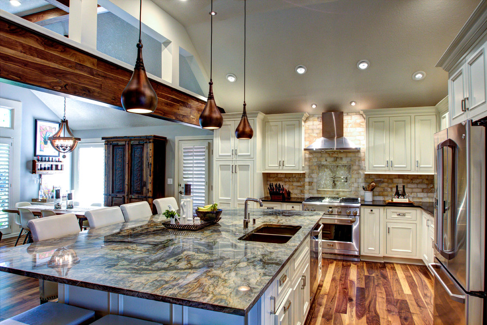 Photo of a large country l-shaped eat-in kitchen in Kansas City with an undermount sink, recessed-panel cabinets, white cabinets, granite benchtops, yellow splashback, stone slab splashback, stainless steel appliances, medium hardwood floors and with island.
