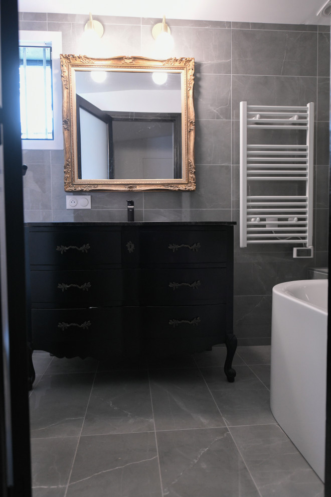 Inspiration for a small eclectic grey and white ensuite bathroom in Paris with a corner bath, a wall mounted toilet, grey tiles, ceramic tiles, grey walls, ceramic flooring, a submerged sink, granite worktops, grey floors, black worktops, a single sink, all types of ceiling and all types of wall treatment.