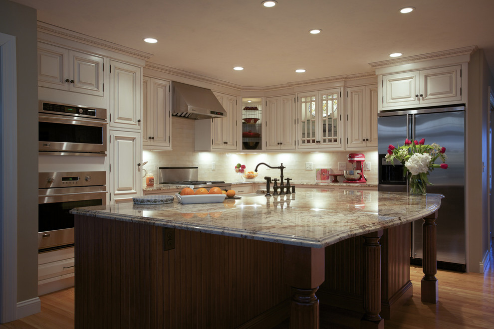 This is an example of a traditional l-shaped kitchen in Boston with a farmhouse sink, raised-panel cabinets, white cabinets and stainless steel appliances.