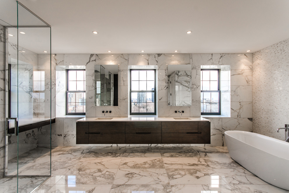 Large contemporary master bathroom in Montreal with flat-panel cabinets, dark wood cabinets, a freestanding tub, a curbless shower, an undermount sink, white tile, white walls, marble floors, solid surface benchtops, marble, multi-coloured floor and a hinged shower door.