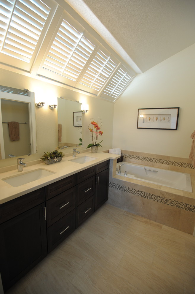 Mid-sized contemporary master bathroom in Orange County with an undermount sink, shaker cabinets, dark wood cabinets, engineered quartz benchtops, a drop-in tub, a one-piece toilet, beige tile, stone tile and travertine floors.