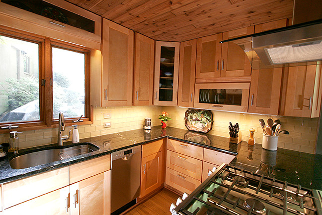 Inspiration for a small transitional l-shaped porcelain tile eat-in kitchen remodel with shaker cabinets, light wood cabinets, granite countertops, beige backsplash, glass tile backsplash, stainless steel appliances and a peninsula