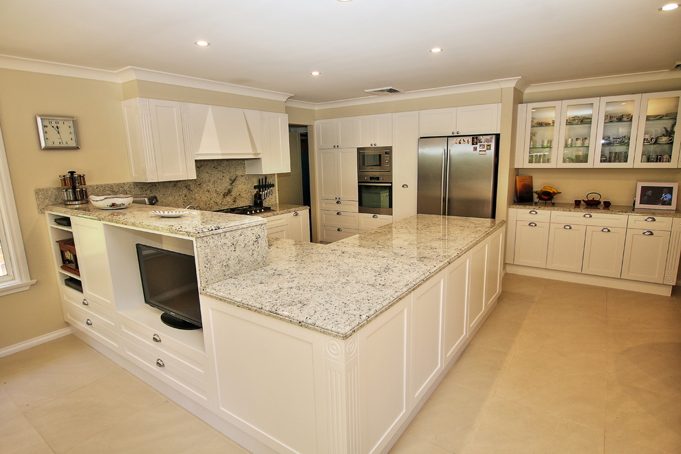 Photo of a large traditional u-shaped eat-in kitchen in Sydney with an undermount sink, shaker cabinets, white cabinets, granite benchtops, multi-coloured splashback, stone slab splashback, stainless steel appliances, ceramic floors and a peninsula.