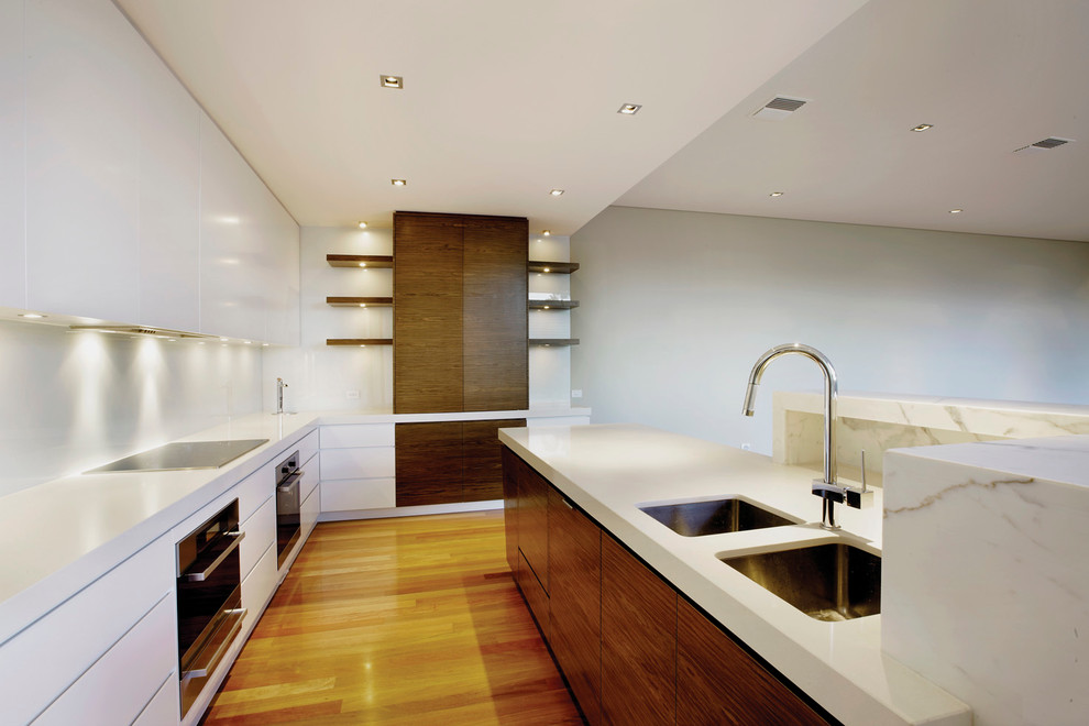 Photo of a contemporary open plan kitchen in Melbourne with an undermount sink, medium wood cabinets, white splashback, glass sheet splashback and stainless steel appliances.
