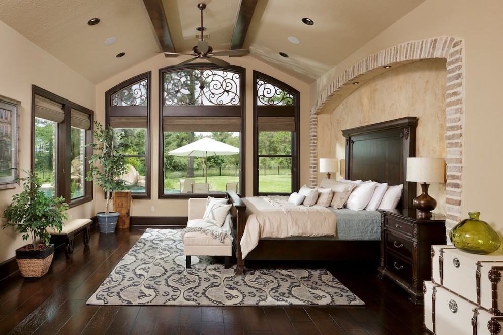 This is an example of a large mediterranean master bedroom in Houston with beige walls and dark hardwood floors.