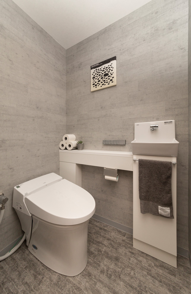 Cette photo montre un WC et toilettes scandinave avec un placard à porte plane, un mur gris et un sol gris.