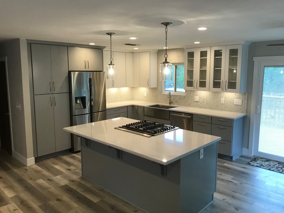 Inspiration for a mid-sized transitional l-shaped laminate floor and gray floor eat-in kitchen remodel with a farmhouse sink, flat-panel cabinets, gray cabinets, quartzite countertops, multicolored backsplash, glass sheet backsplash, stainless steel appliances, an island and white countertops
