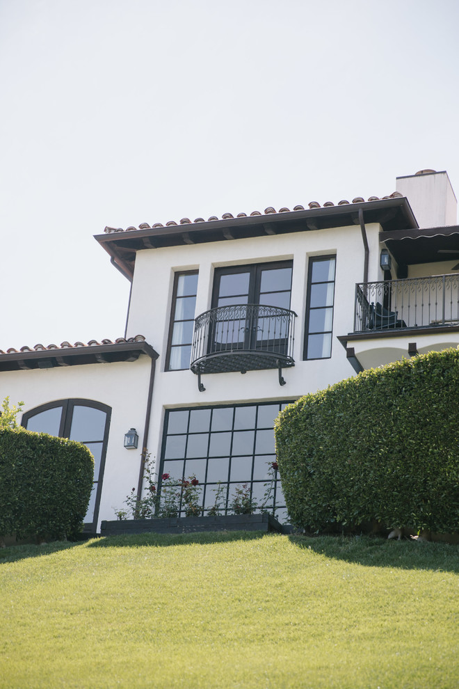 Photo of a mediterranean two-storey concrete white house exterior in Los Angeles with a gable roof and a tile roof.