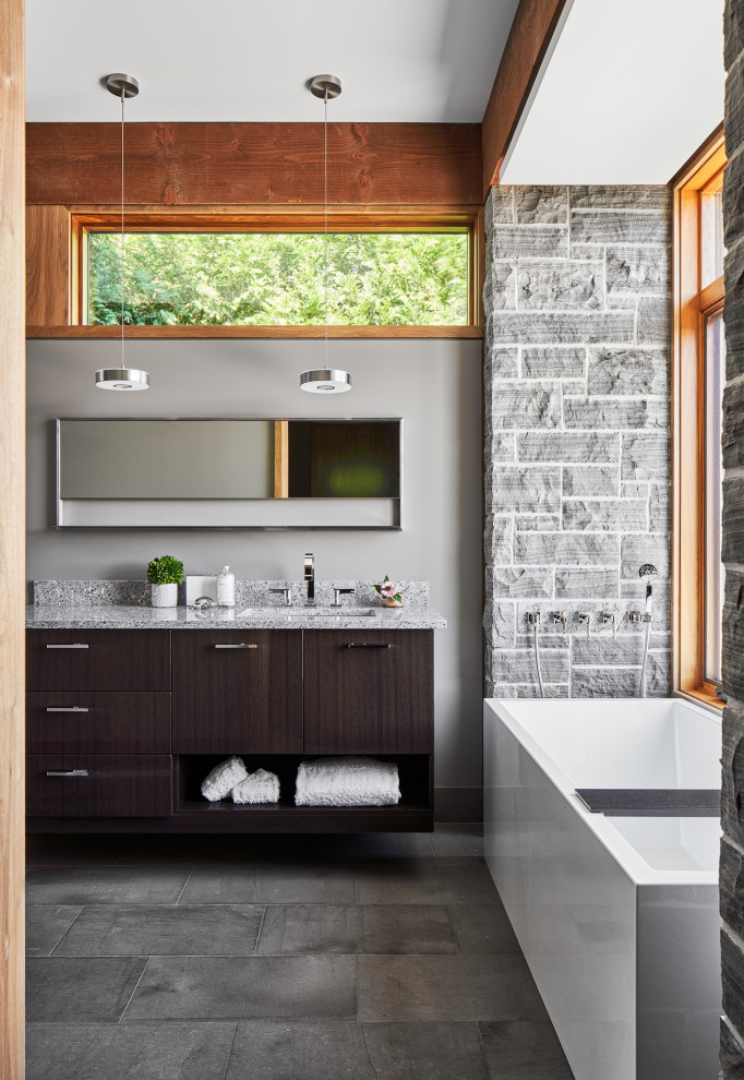 Photo of a country bathroom in Ottawa with flat-panel cabinets, dark wood cabinets, a freestanding tub, gray tile, stone tile, grey walls, an undermount sink, grey floor, grey benchtops, a double vanity and a floating vanity.