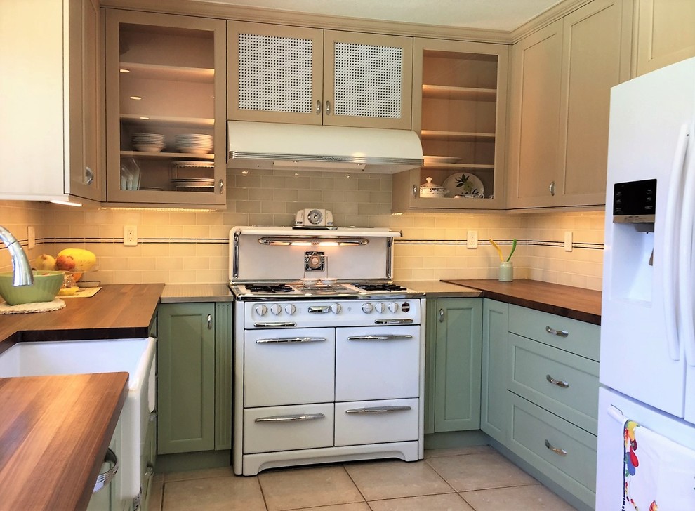 This is an example of a mid-sized country u-shaped separate kitchen in Orange County with a farmhouse sink, shaker cabinets, green cabinets, wood benchtops, green splashback, ceramic splashback, white appliances, porcelain floors and no island.