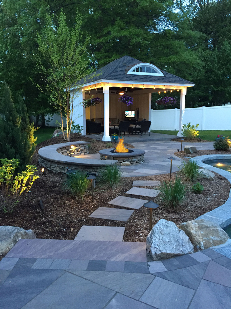 This is an example of a large traditional backyard patio in Bridgeport with a fire feature, natural stone pavers and a gazebo/cabana.