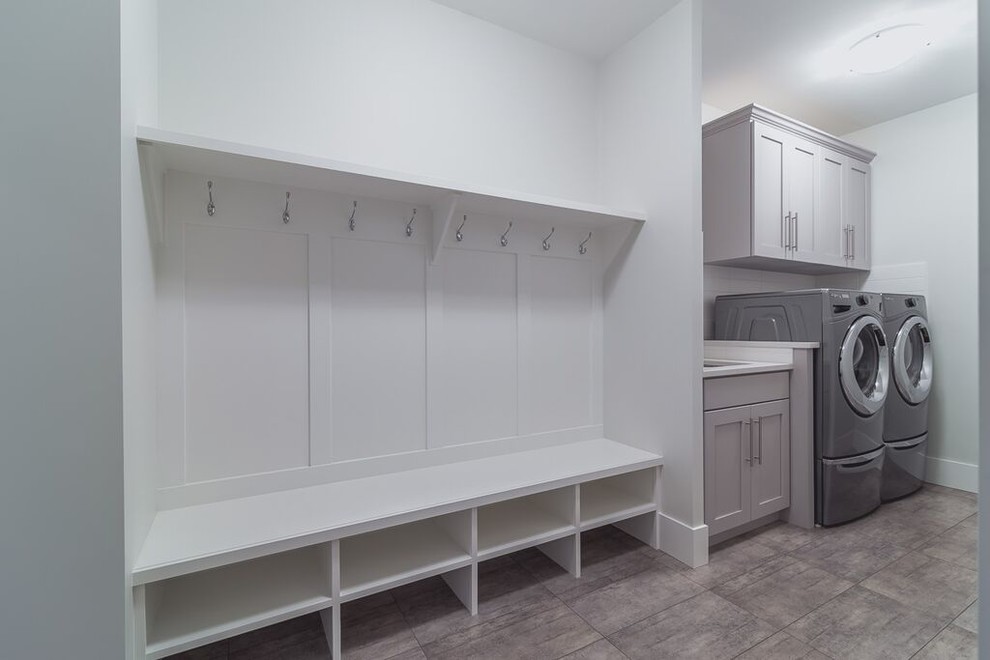 Design ideas for a mid-sized contemporary single-wall utility room in Vancouver with an undermount sink, shaker cabinets, grey cabinets, quartz benchtops, white walls, ceramic floors and a side-by-side washer and dryer.