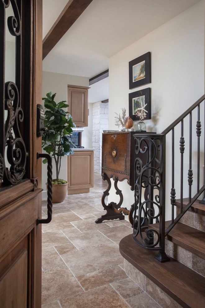 Design ideas for a large mediterranean foyer in Orange County with white walls, travertine floors, a single front door, a dark wood front door and brown floor.