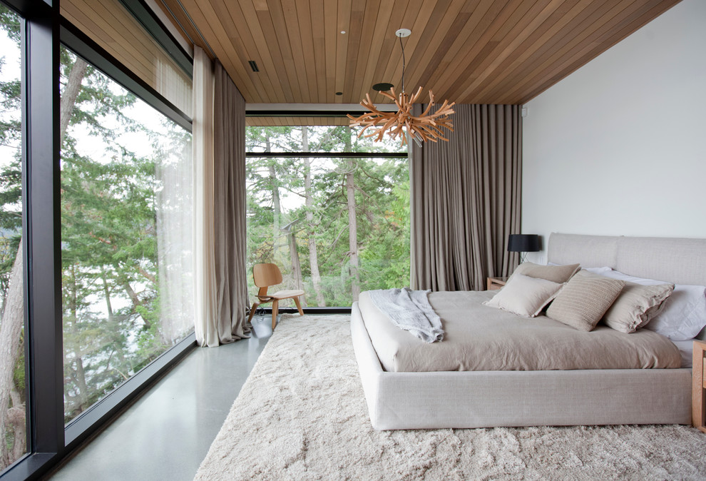 Large modern master bedroom in Vancouver with white walls, concrete floors and no fireplace.
