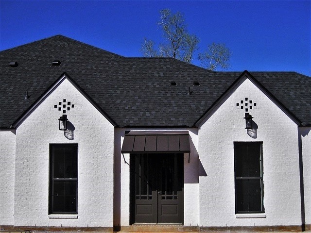 Example of a mid-sized trendy gray one-story stucco house exterior design in New Orleans with a hip roof and a shingle roof
