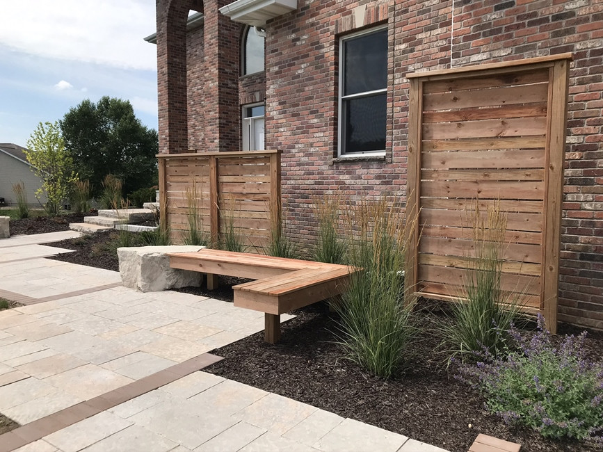 This is an example of a mid-sized contemporary front yard full sun garden in Milwaukee with with path, natural stone pavers and a wood fence.