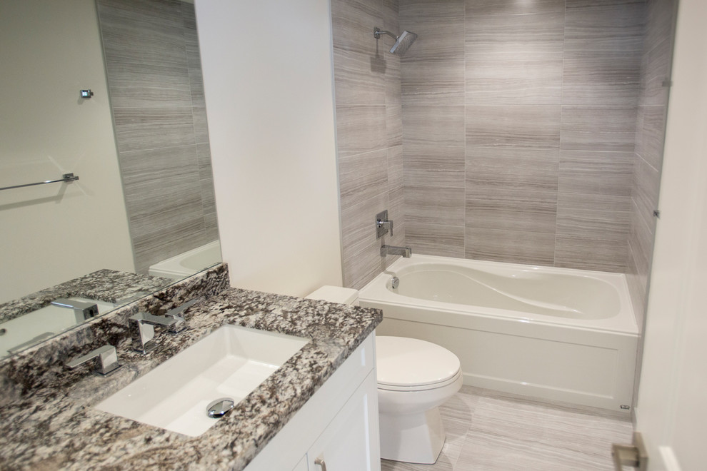 This is an example of a mid-sized modern 3/4 bathroom in Vancouver with shaker cabinets, white cabinets, an alcove tub, a shower/bathtub combo, a two-piece toilet, beige tile, gray tile, matchstick tile, blue walls, an undermount sink and granite benchtops.
