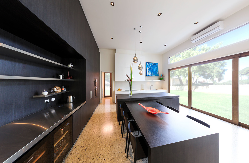 Large contemporary eat-in kitchen in Melbourne with flat-panel cabinets, white splashback, stainless steel appliances, concrete floors and with island.