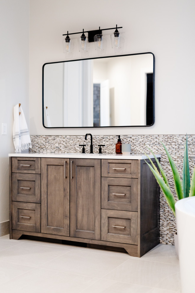 Photo of a large beach style master bathroom in Denver with recessed-panel cabinets, medium wood cabinets, a freestanding tub, an alcove shower, gray tile, pebble tile, cement tiles, quartzite benchtops, beige floor, an open shower, white benchtops, a double vanity and a freestanding vanity.