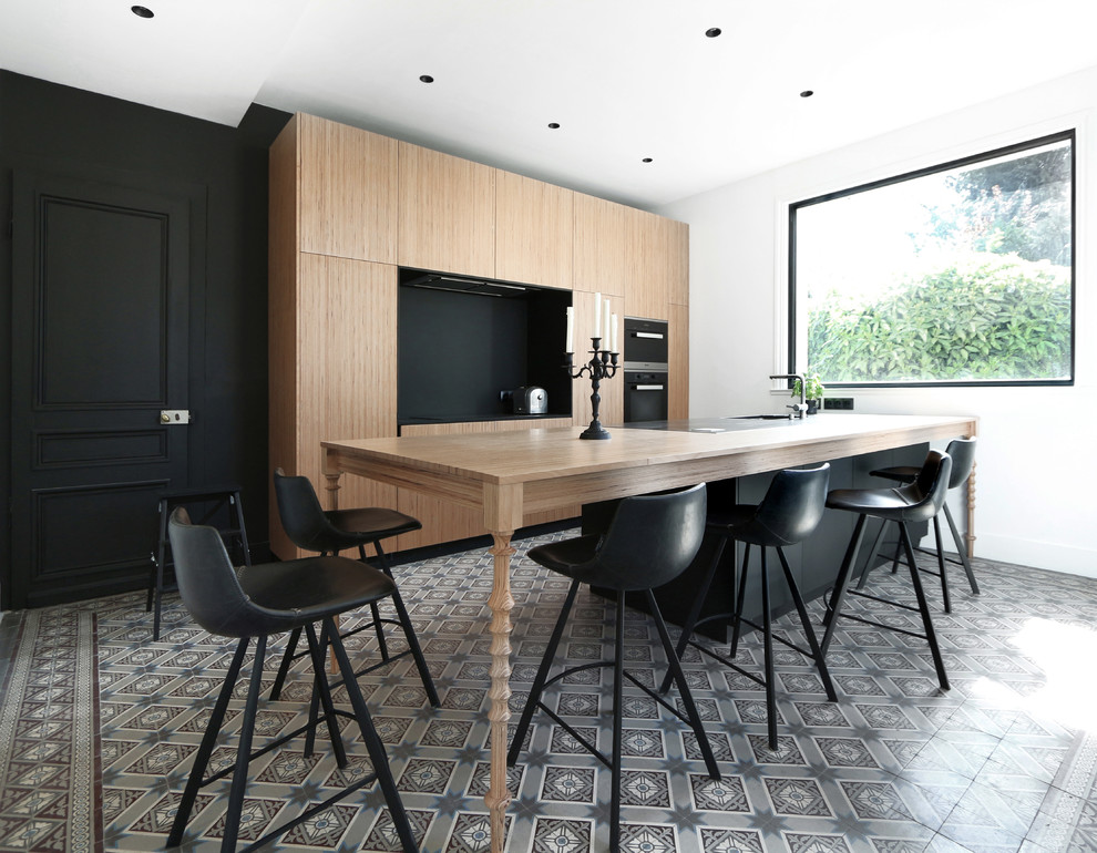 Inspiration for a contemporary galley kitchen in Lille with flat-panel cabinets, medium wood cabinets, wood benchtops, black splashback, stainless steel appliances, with island, grey floor and brown benchtop.