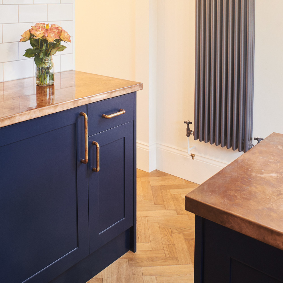 Small industrial u-shaped separate kitchen in Sussex with a farmhouse sink, shaker cabinets, blue cabinets, copper benchtops, white splashback, subway tile splashback and stainless steel appliances.