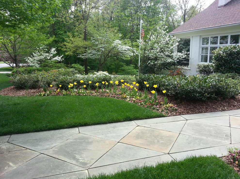 Large transitional front yard partial sun garden in Raleigh with natural stone pavers for spring.