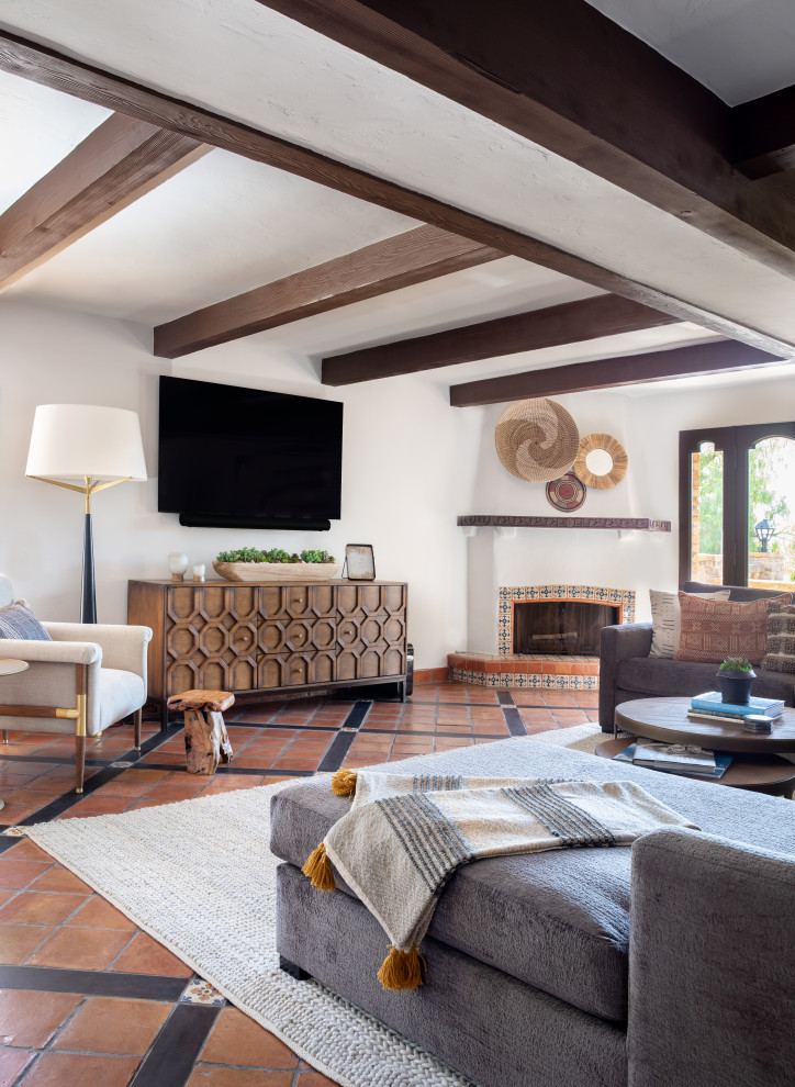 На фото: большая открытая гостиная комната в средиземноморском стиле с домашним баром, полом из терракотовой плитки, угловым камином, фасадом камина из камня, телевизором на стене, оранжевым полом и балками на потолке