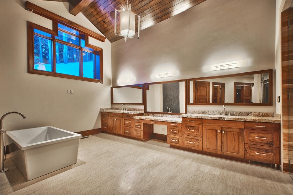 This is an example of an expansive contemporary master bathroom in Salt Lake City with raised-panel cabinets, dark wood cabinets, a freestanding tub, beige walls, porcelain floors, an undermount sink, granite benchtops and beige floor.