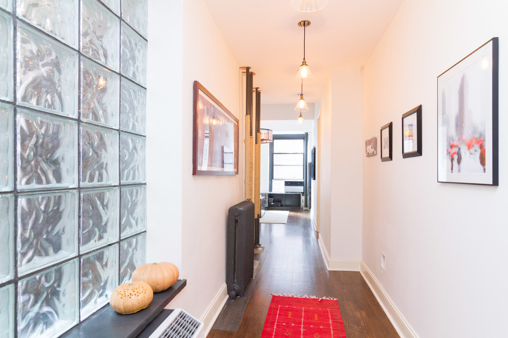 This is an example of a mid-sized traditional hallway in New York with white walls, dark hardwood floors and brown floor.