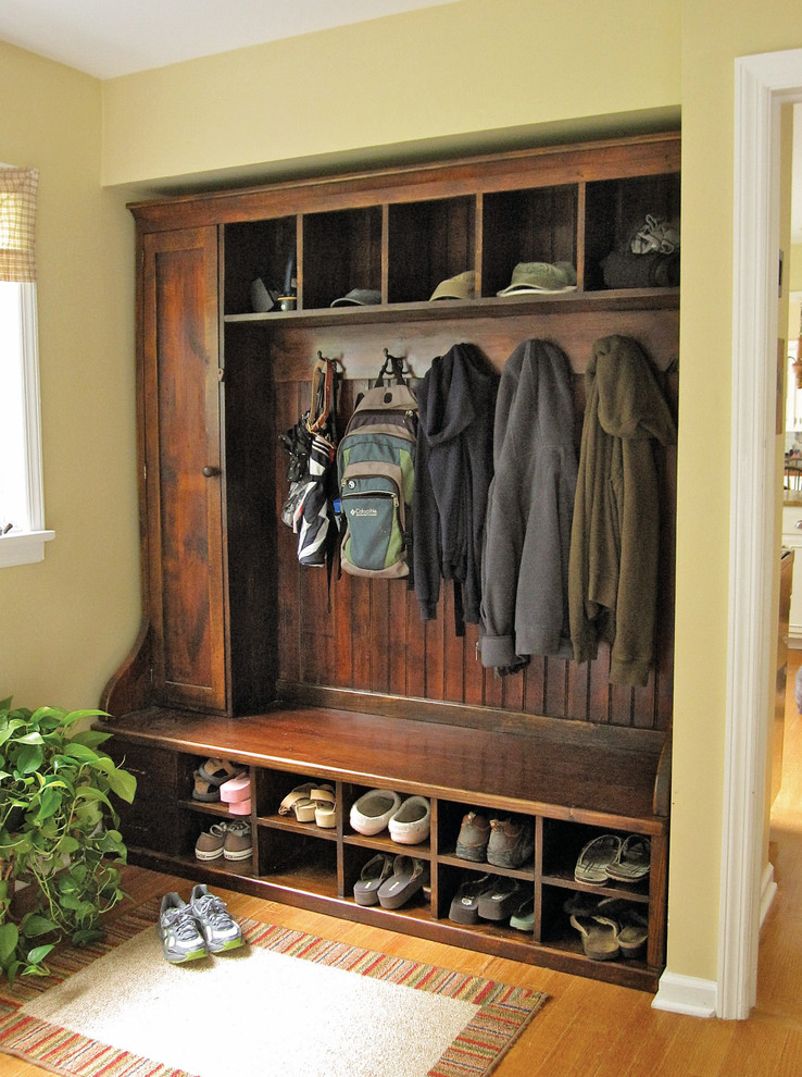 Photo of a mid-sized traditional mudroom in New York with yellow walls and medium hardwood floors.