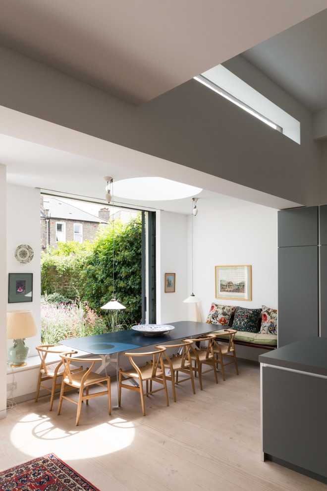 Photo of a mid-sized contemporary open plan dining in London with white walls, light hardwood floors and beige floor.