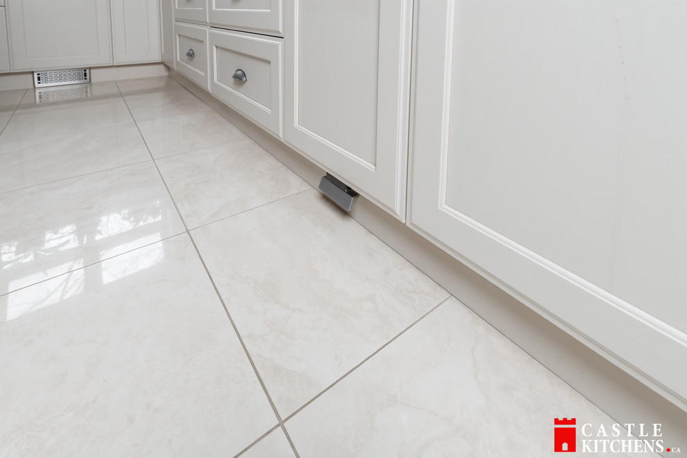 Inspiration for a mid-sized transitional galley porcelain tile home design remodel in Toronto with an undermount sink, shaker cabinets, beige cabinets, quartzite countertops, beige backsplash, stainless steel appliances and an island